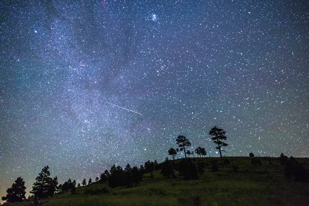 As chuvas de meteoros são fenômenos regulares. Na imagem， é possível ver o céu noturno perto das colinas próximas ao Pico O'Leary， no Arizona， Estados Unidos. Ao centro， um brilhante meteoro cruza o céu. — Foto: Domínio Público/Wikimedia